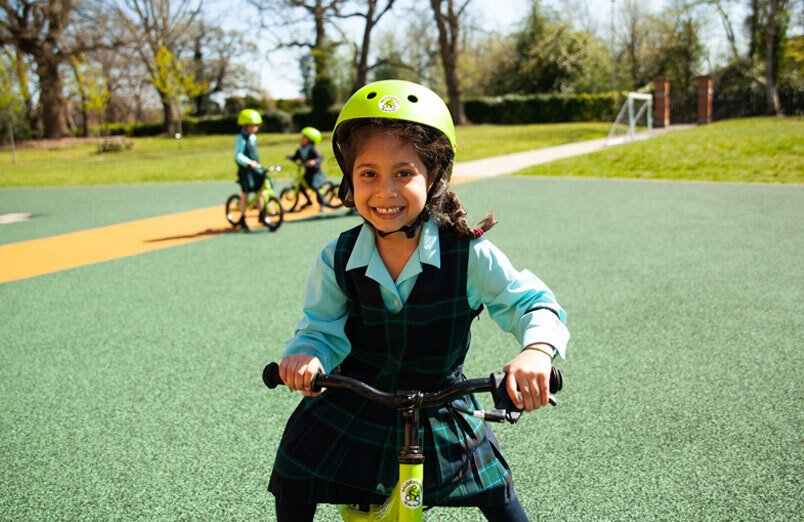 St Margarets School Balanceability workshop girl smiling and riding bike in playarea