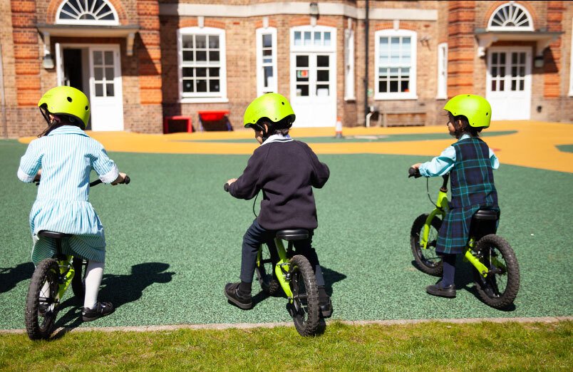 St Margarets School Balanceability workshop three pupils learning to ride bikes in playground