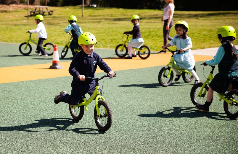 St Margarets School Balanceability workshop boy smiling and balancing on balance bike with other children